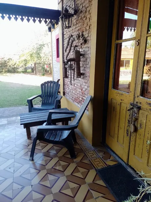Sillones en la galería, frente al césped del parque.