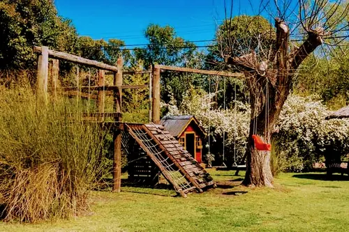 Juegos de madera con tobogán y trepadora en el parque.