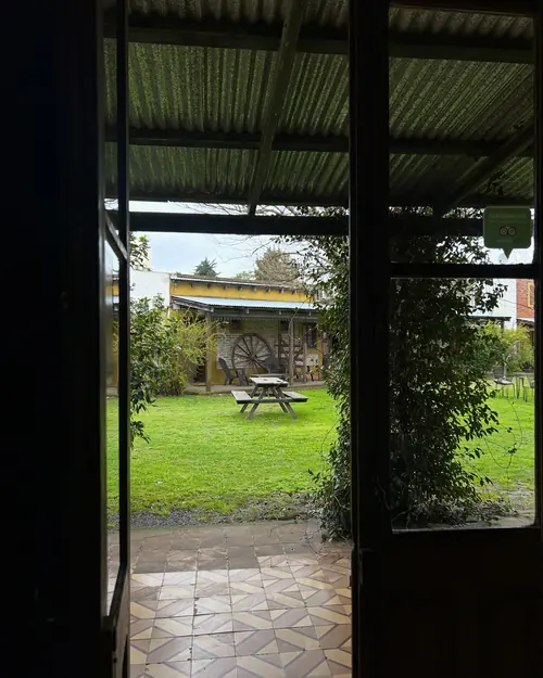 La puerta de la suite abierta hacia la galería con baldosas y el parque.
